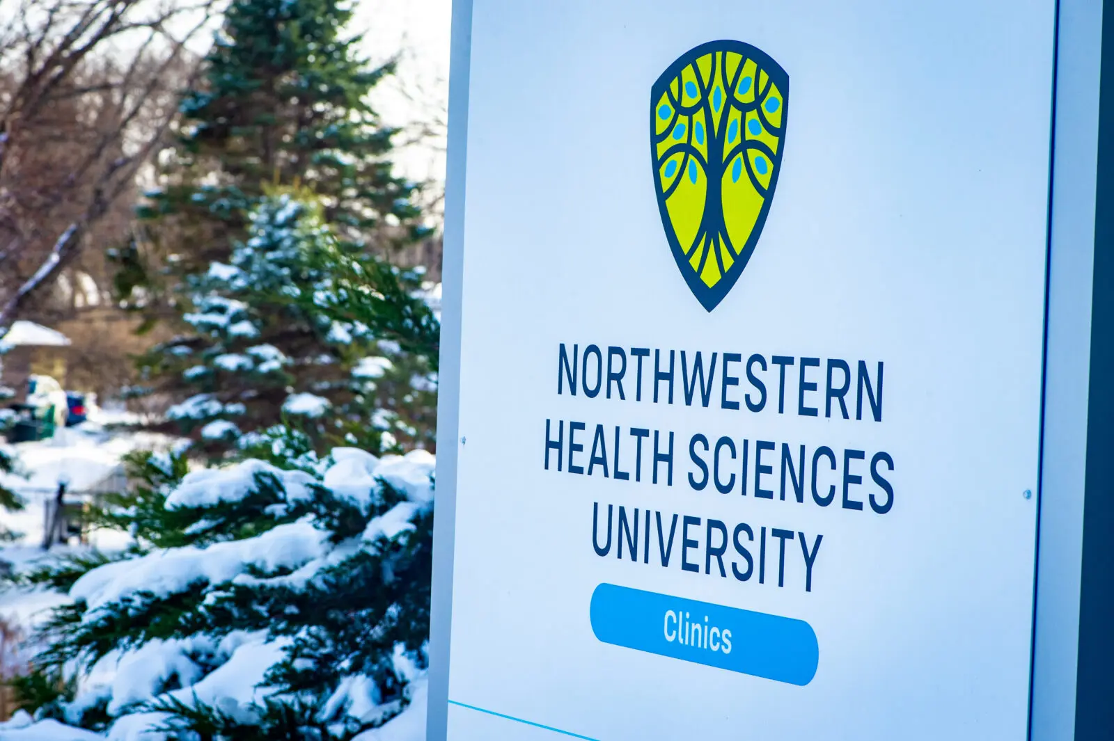 Sign for Northwestern Health Sciences University with their tree logo and the text “Clinics” on a blue pill-shaped button.