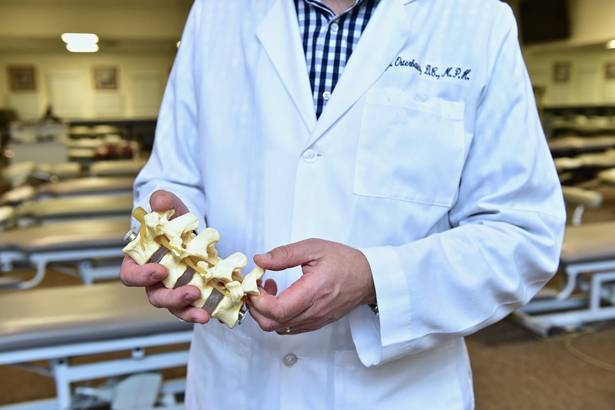 Chiropractic instructor holds model of vertebrae