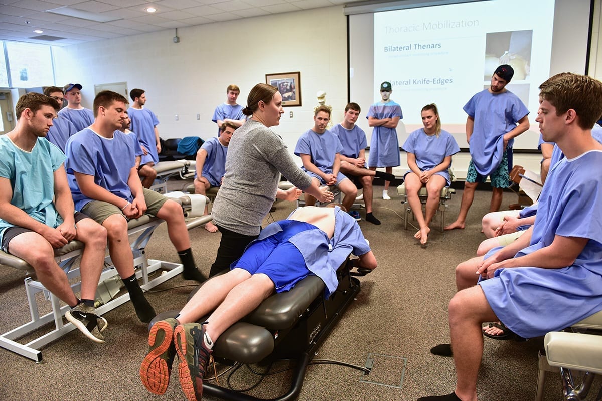 Chiropractic instructor demonstrates a technique for a group of students